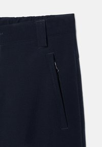 Pantalon marine avec une texture lisse, doté d'une poche latérale zippée et d'une taille élastique pour un ajustement réglable. Design épuré, sans motifs.