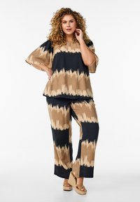 Twee-delige outfit met een losse, kort mouwtop en wijde broekspijpen. De stof toont een bruin en zwart golfpatroon met een gestructureerde afwerking.