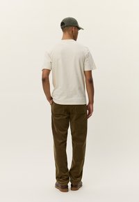 Beige cotton t-shirt, slim fit, paired with brown corduroy pants and brown shoes. Simple design, no visible logos or patterns.