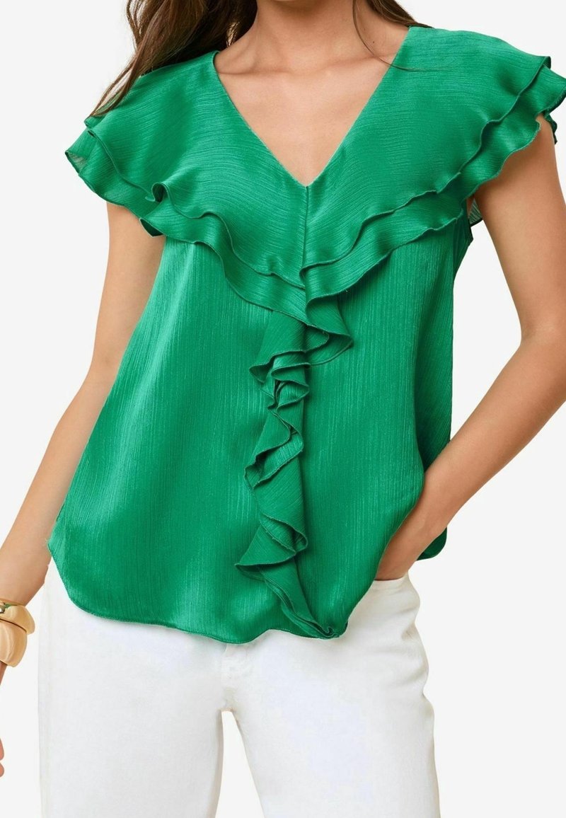 Blusa verde con scollo a V con volant, maniche corte e texture liscia. Presenta un dettaglio centrale a volant che corre lungo il fronte.