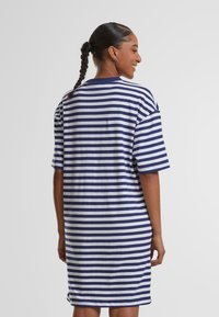 Blauw-wit gestreepte oversized t-shirt jurk met korte mouwen, een ronde hals en een zachte katoenen textuur, die tot halverwege de bovenbenen reikt.