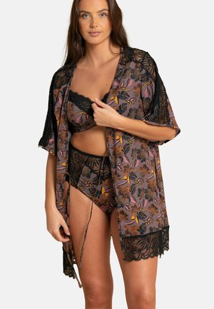 Kimono avec des bordures en dentelle à imprimé floral foncé et accents orange et rose, porté sur un soutien-gorge en dentelle noir et un bas assorti. Tissu doux et fluide.