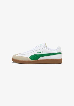 White sneaker with green accents featuring a smooth synthetic upper, beige suede toe cap, and a gum rubber sole. Laces and logo are prominently displayed.