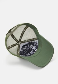 Zöld sapka hálós hátsó résszel. Ívelt karimával és mintás béléssel, fekete grafikákkal. Állítható pattintós zár a hátsó részen.
