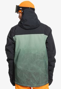 Chaqueta de nieve para hombres con una combinación de colores en verde oscuro y negro, acabado texturizado, capucha y diseño de panel superior en contraste.