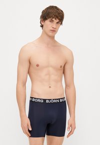 Ναυτικά μποξεράκια από ελαστικό ύφασμα με μαύρη ζώνη που διαθέτει το λογότυπο "BJÖRN BORG" σε λευκό χρώμα. Σχηματισμένο σχέδιο που ενισχύει τη συνολική σιλουέτα.