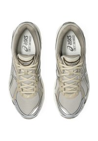 Beige running shoes with a textured mesh upper, synthetic overlays, reflective accents, and a cushioned sole. Laces are positioned centrally.