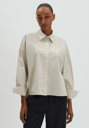 Beige button-up shirt with subtle vertical stripes, oversized fit, and cuffed sleeves. Made from smooth fabric with a classic collar design.