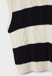Pull sans manches tricoté avec un motif en torsades, présentant des rayures crème et marine alternées. L'ourlet côtelé offre une finition texturée.