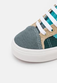 Tenisky s panely z kordu v zelené, tan a teal barvě, bílými tkaničkami a gumovou podrážkou, které vystihují texturované povrchy a vícebarevný design.