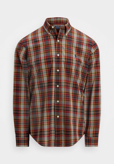 Chemise à manches longues à carreaux présentant des tons de rouge, jaune et gris. Modèle avec col et poignets à deux boutons. Logo Polo sur la poitrine.