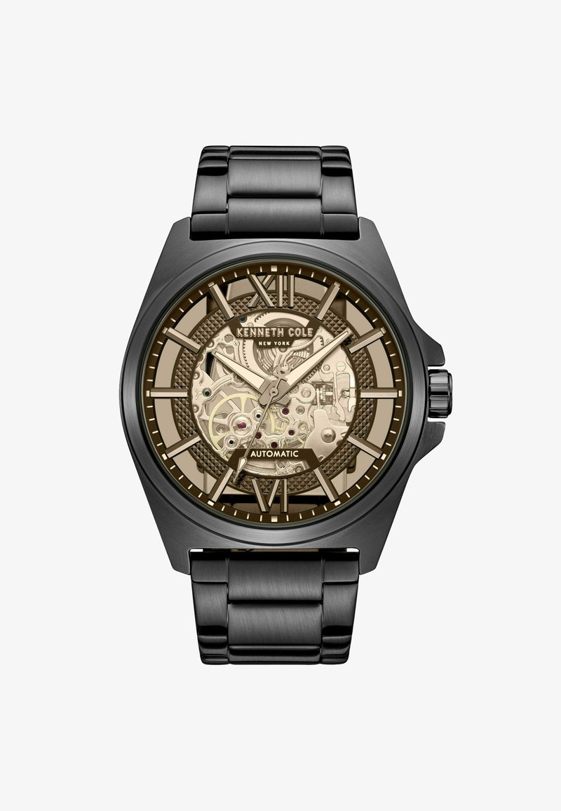 Zwarte stainless steel automatische horloge met een transparante beige wijzerplaat, ingewikkelde tandwielen en gedurfde uurmarkeringen, voorzien van een patroonrand.