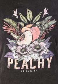 Musta graafinen t-paita, jossa on persikan kuvasto, jota ympäröivät vihreät lehdet ja purppurat kukat. Tekstissä lukee "PEACHY AS CAN BE."