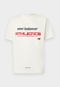 Balts kokvilnas t-krekls ar melnu un sarkanu "new balance" un "ATHLETICS" tekstu, ar dzeltenu logo detaļu un "BOSTON, MA." mazā melnā drukā.