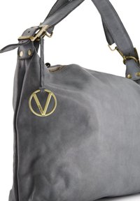 Grijze lederen tas met een gladde textuur, gouden hardware, een verstelbare schouderband en een ronde logo charm bevestigd bij de rits.
