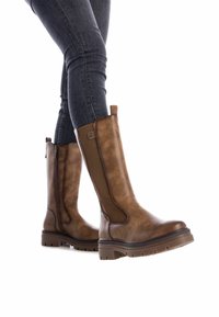 Stivali al ginocchio in pelle marrone con finitura testurizzata, zip laterale e suola in gomma robusta, abbinati a jeans scuri.