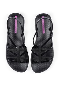 Schwarze Sandalen mit strukturiertem Fußbett, die mehrere dünne Riemen und einen lila Logo-Akzent aufweisen. Das Material wirkt elastisch und langlebig.