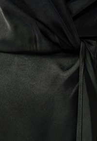 Black satin fabric featuring a smooth texture with draped sections and a tied accent. Subtle sheen enhances depth and sophistication.
