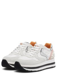 White suede and leather sneakers with orange accents, reflective details, and a textured spike design on the heel. Black and white sole.