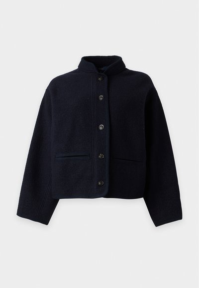 Veste en laine bleu marine foncé avec boutons, col montant et deux poches avant, présentée sur un fond clair uni.