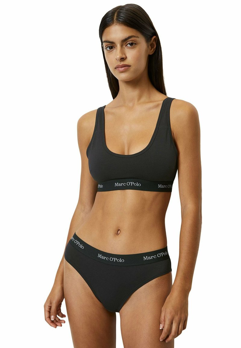 Soutien-gorge noir sans fil en coton doux et culotte hipster assortie avec une taille élastique logo, présentant une texture lisse et un design simple.