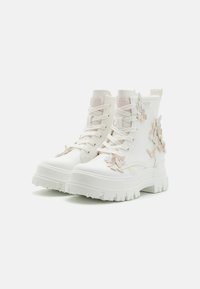 Witte gevechtslaarzen met een stevige, gestructureerde zool. Bevat decoratieve, pastelkleurige vlinderaccenten aan de zijkanten. Vetersluiting met versterkte hiel.