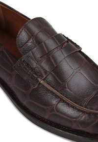 Brown leather loafer with a textured croc pattern, a stitched strap detail, and a smooth finish along the upper edge and sole.