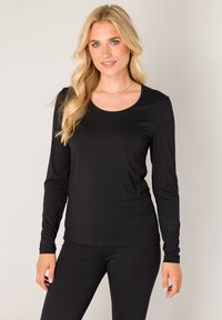 Zwart topje met lange mouwen en een ronde hals, gemaakt van een gladde, rekbare stof. Gecombineerd met bijpassende zwarte leggings voor een samenhangende uitstraling.