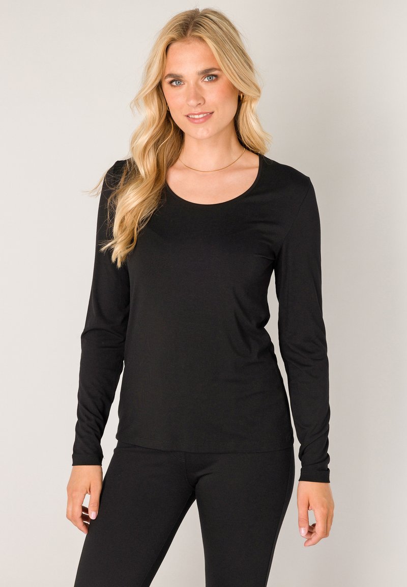 Zwart topje met lange mouwen en een ronde hals, gemaakt van een gladde, rekbare stof. Gecombineerd met bijpassende zwarte leggings voor een samenhangende uitstraling.