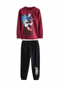 Triko s dlouhým rukávem v barvě burgundy s grafickým designem na téma Sonic, spárované s černými kalhotami na gumu s logem v růžové a bílé barvě.