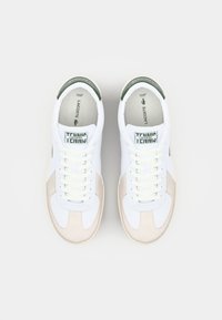White sneakers with beige and green accents, featuring leather and textile materials, round toe, flat laces, and logo detail on the tongue.