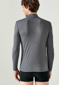 Polo shirt grigio a maniche lunghe con colletto, realizzato in tessuto liscio e elasticizzato, design aderente e orlo dritto.
