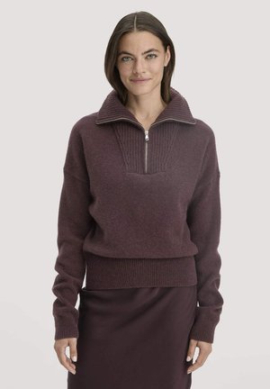 Burgunderfarbener Pullover mit hohem Kragen, halbem Reißverschluss vorne, gerippter Textur und enganliegender Passform. Kombiniert mit einem passenden, taillierten Rock.