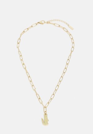 Goldene Kettenhalskette mit großen, länglichen Gliedern und einem dekorativen Charme in Form einer Hand, verziert mit grünen, glitzernden Akzenten.