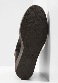 Semelle de chaussure noire avec grip texturé, marquage taille 37, et branding "Refugie", positionnée verticalement sur un fond blanc.