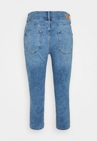 Jean cropped en denim bleu avec une coupe droite, doté de deux poches arrière et d'un léger décoloration, terminé par une ceinture cousue et un patch de logo.
