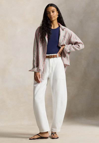 Ριγέ πουκάμισο με κουμπιά σε ροζ και πράσινο, συνδυασμένο με μπλε μπλούζα, λευκό παντελόνι με φαρδιά πόδια και καφέ πλεκτή ζώνη. Σανδάλια ολοκληρώνουν το ντύσιμο.