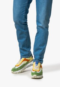 Sneaker multicolori con una combinazione di giallo, verde, arancione e crema, caratterizzati da materiali in suede e mesh, una suola spessa e lacci a contrasto.