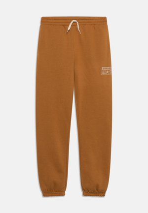 Pantalons de survêtement en coton marron avec une taille élastique et un cordon de serrage, présentant des poignets côtelés et un logo imprimé sur la cuisse gauche.
