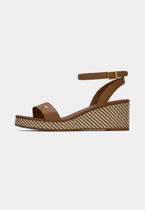 Brown leather wedge sandals with a wide toe strap, ankle strap, and striped woven platform. Gold hardware detail near the toe.