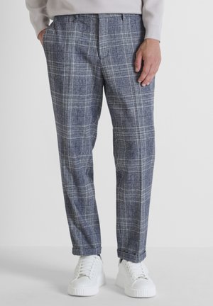 Grijze geruite broeken met een relaxte pasvorm, voorzien van een ruitenpatroon en zijzakken, gecombineerd met witte sneakers.