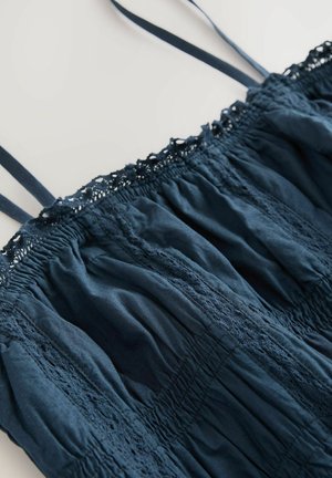 Námornícky modrý bezrukávový top vyrobený z ľahkého materiálu, so zhrnutou textúrou a čipkovými akcentmi pozdĺž výstrihu a ramienok.