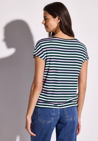 Camiseta a rayas en verde con líneas blancas y rosas, con cuello redondo y mangas cortas, combinada con jeans de mezclilla azul.