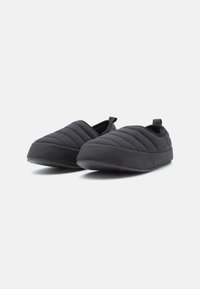 Črne slip-on čevlje s quilted vzorcem, okroglo točko in fleksibilnim gumijastim podplatom. Material se zdi gladek z diskretno teksturo in zanko za poteg.