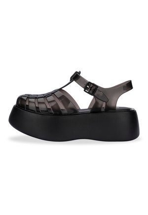 Sorte platformsandaler med et gennemsigtigt, vævet overdesign, justerbar spænde og en tekstureret sort sål.