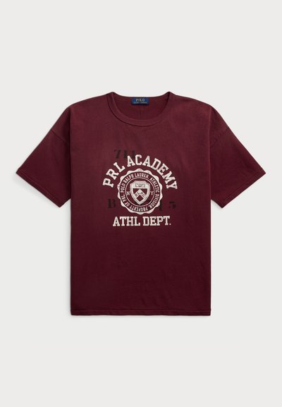 Bordeaux T-shirt gemaakt van katoen, met witte bedrukte tekst "PRL ACADEMY ATHL DEPT." en een schildafbeelding in het midden. Korte mouwen.