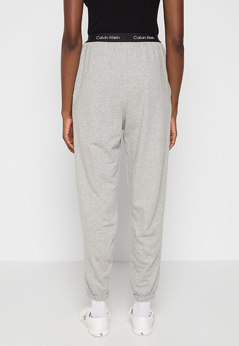 Pantaloni della tuta grigi con un elastico in vita nero di Calvin Klein, caratterizzati da un design con gamba affusolata e polsini elasticizzati alle caviglie.