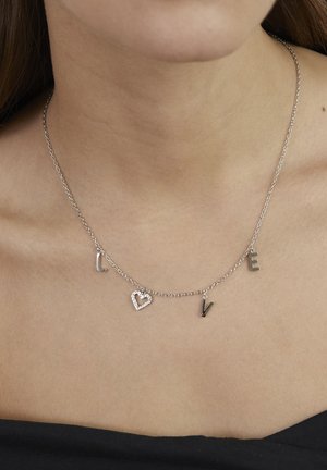 Silberne Halskette mit den Buchstaben "L", "O", "V", "E" und einem Herzanhänger mit klaren Steinen. Einfaches Design, geeignet für verschiedene Anlässe.
