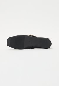 Escarpin noir à talon haut avec un dessus en cuir lisse, détail de boucle ajustable et semelle en caoutchouc texturé pour une meilleure adhérence.