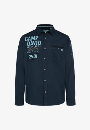 Marineblauwe longsleeve shirt met een voorzak, knoopsluiting en grafische tekst in lichtblauw en oranje. Soepele, casual katoenen stof.